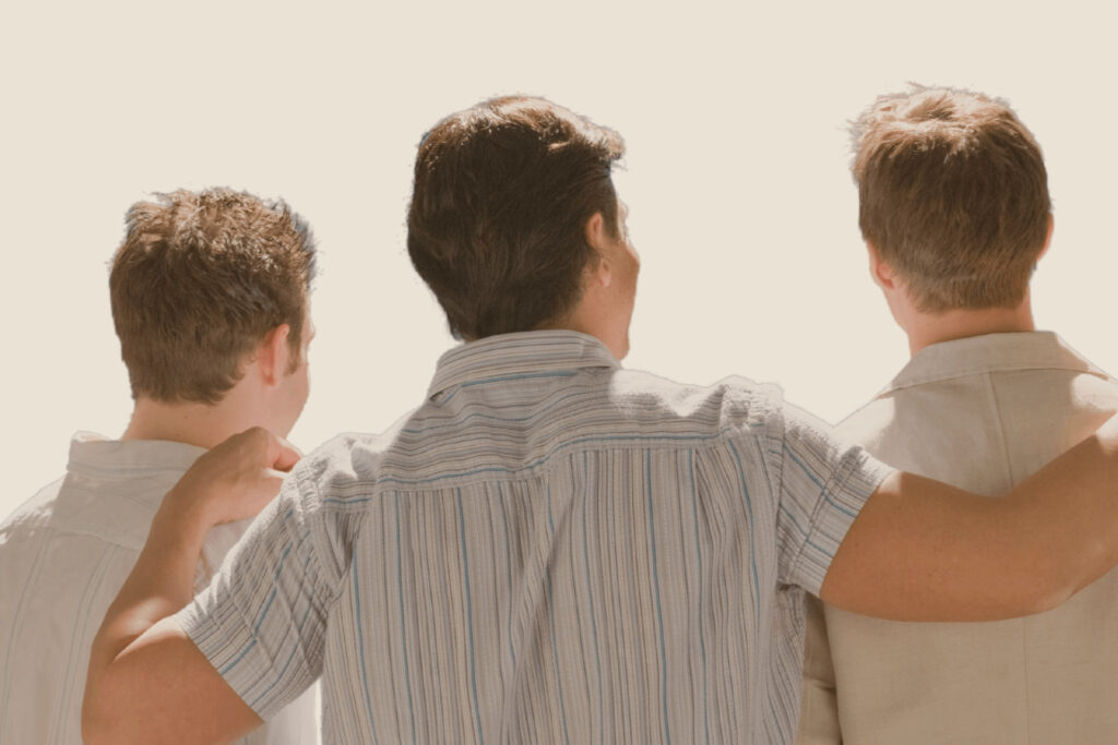Tres hermanos adultos de espaldas, abrazados por los hombros, simbolizando unión familiar en el contexto de una herencia compartida